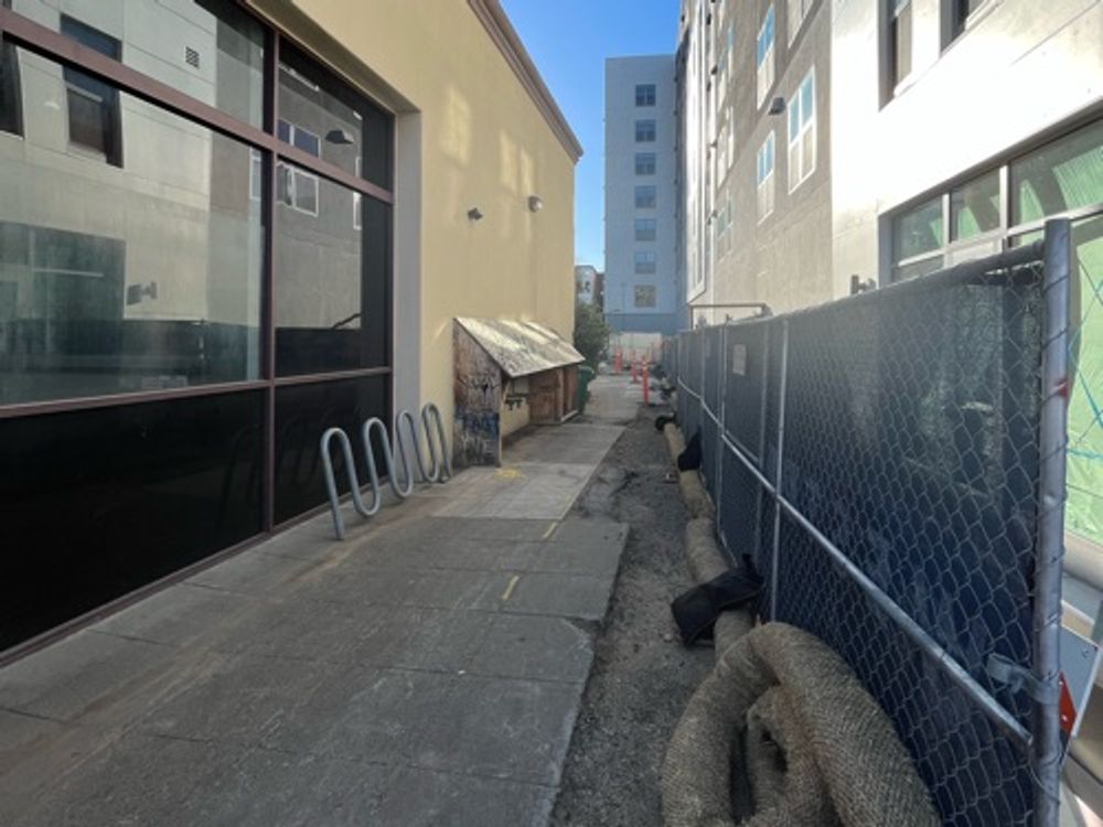 Thin alleyway behind new looking building — image 1